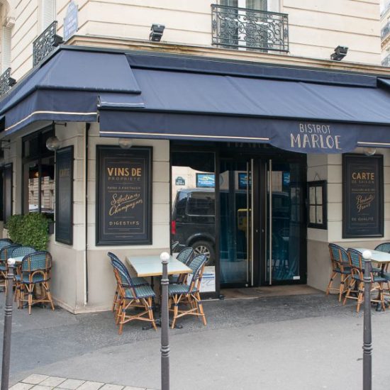 Terrasse extérieur du restaurant Le Marloe de Paris. Chaises en cannage par Maison Gatti. Store et panneaux décor bleu marine.