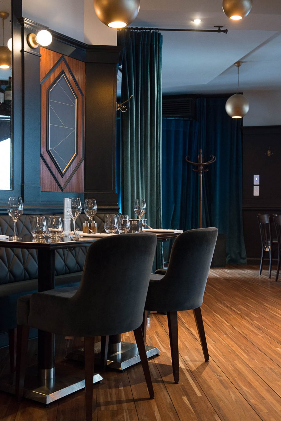Intérieur du restaurant Le Marloe de Paris avec banquette en cuir matelassé, parquet et panneaux décoratifs de bois au motif hexagonal