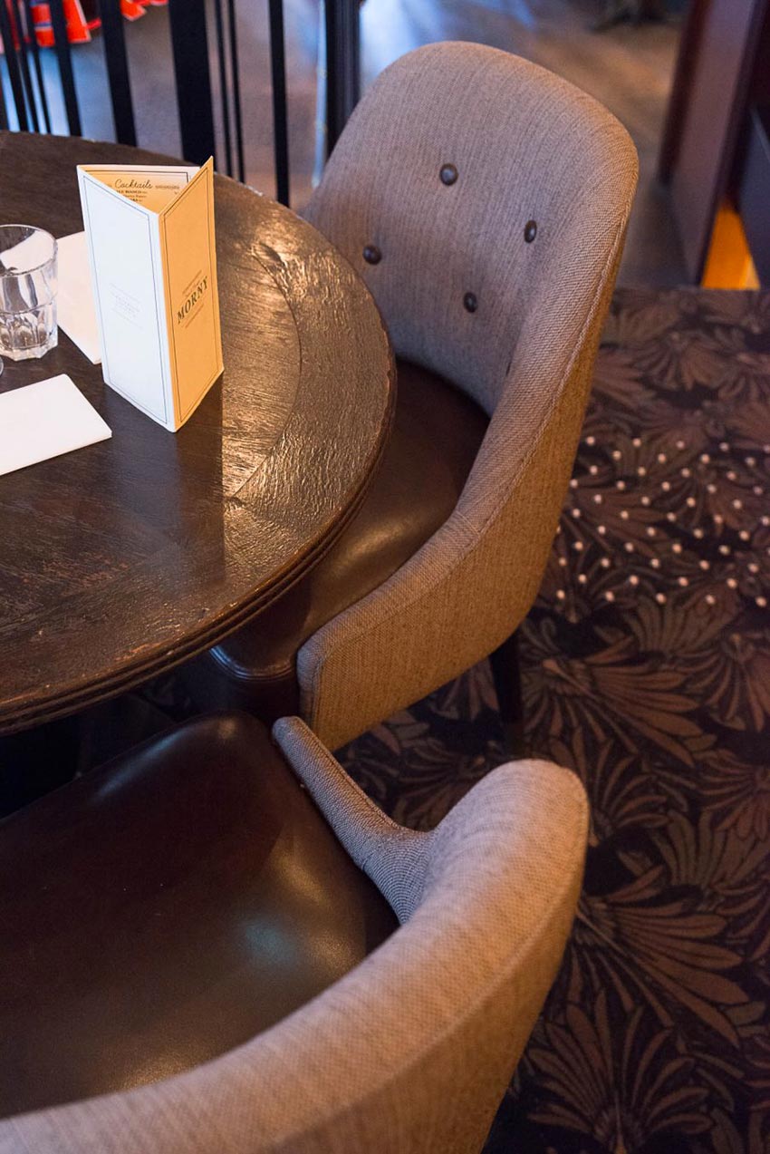Intérieur du restaurant Le Morny de Paris, moquette au sol et fauteuils avec assises en cuir. Décoration par le Studio Emma Roux