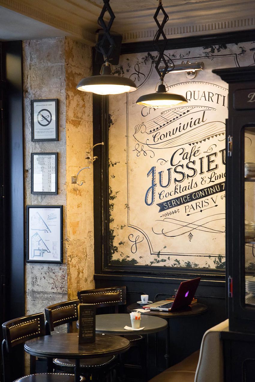 Intérieur du Café Jussieu de Paris avec son panneau décor, ses suspensions croisillon et ses assises en cuir.